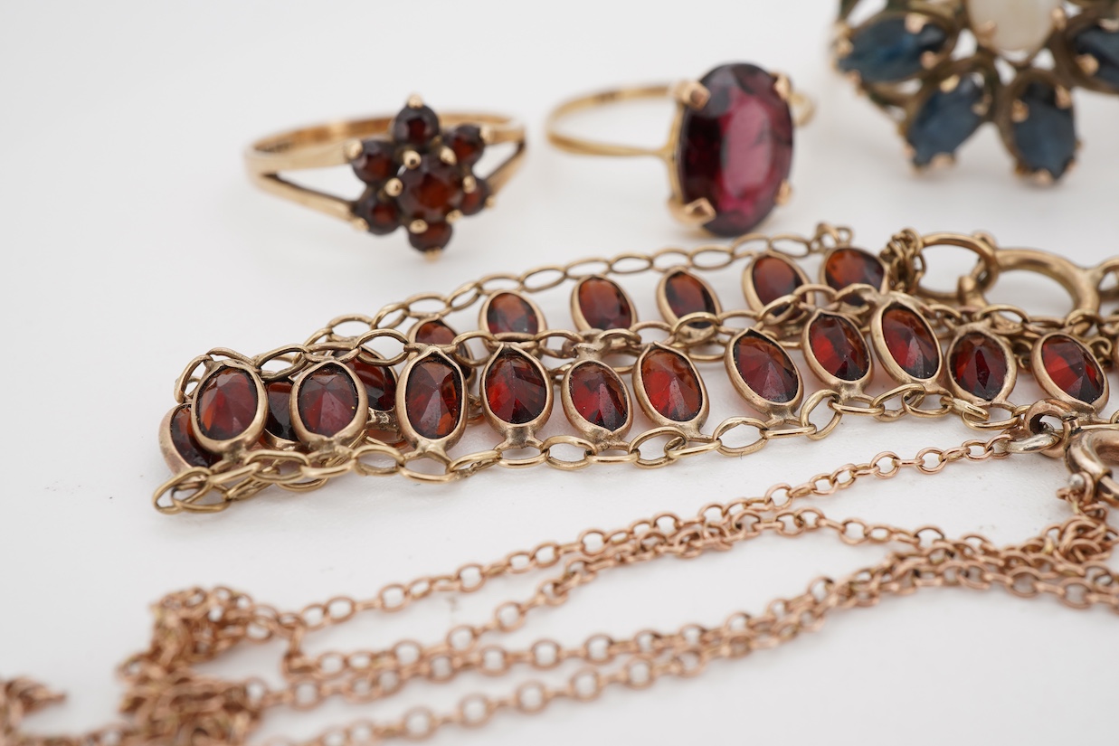 A group of jewels, comprising: two garnet cluster rings; a garnet bracelet; and a blue topaz ring, each mounted in 9ct gold, ring sizes H-M1/2, combined gross weight 13 grams; together with a marquise-shaped sapphire and